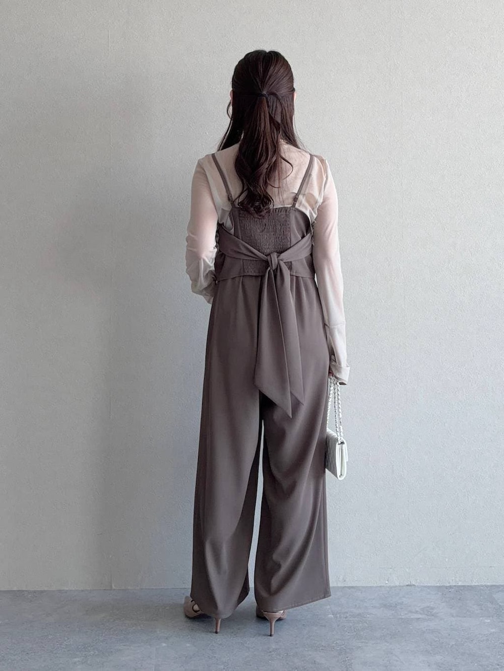 ブラウン系のサンダル、ホワイト系のショルダーバッグ、ベージュ系のパンツドレスを着用したレディースの春コーディネートの2枚目の写真