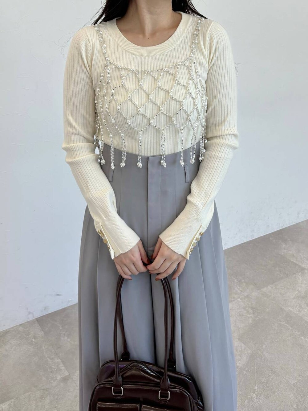 ブラウン系のブーツ、ホワイト系のニット/セーター、ブラウン系のハンドバッグを着用したレディースの冬コーディネートの3枚目の写真