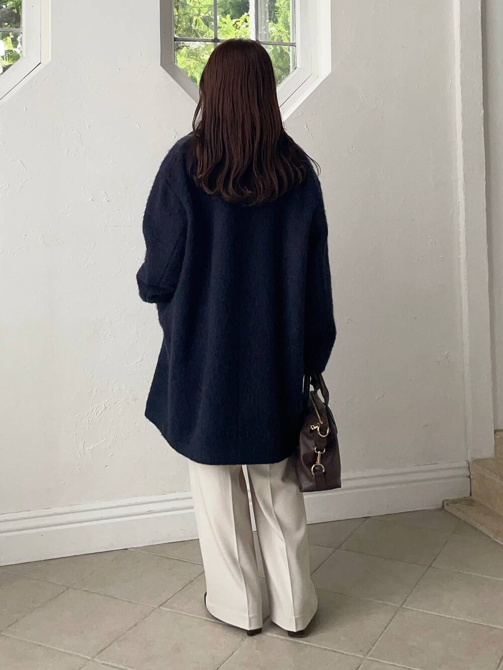 ブラウン系のボストンバッグ、ブルー系のチェスターコート、ブラウン系のブーツを着用したレディースの秋コーディネートの2枚目の写真