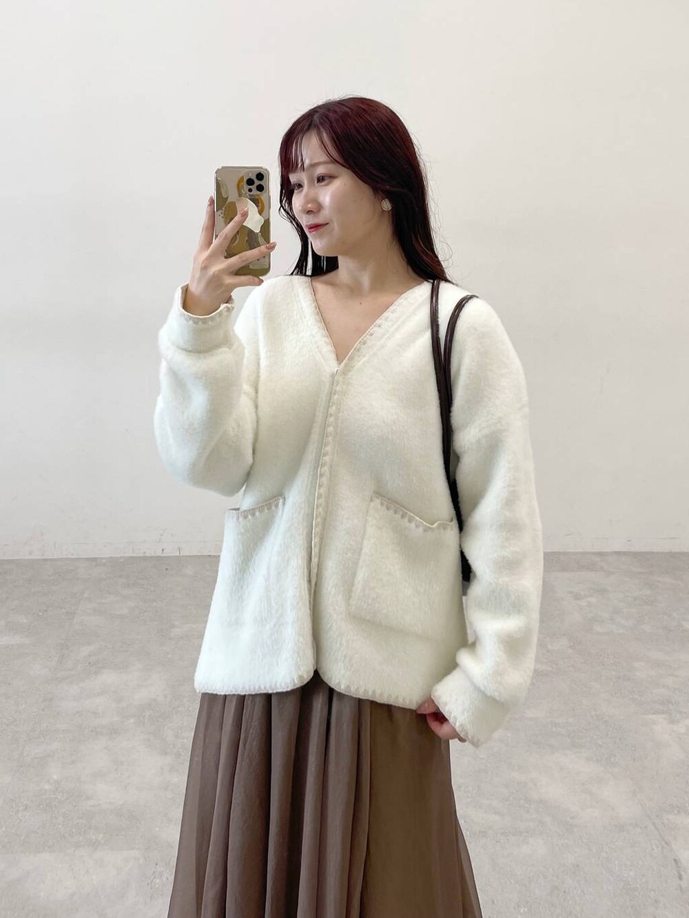 ブラック系のブーツ、ブラウン系のハンドバッグ、ホワイト系のブルゾンを着用したレディースの秋コーディネートの7枚目の写真