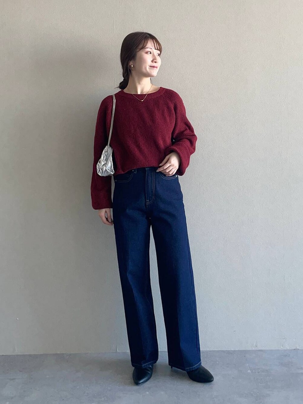 レッド系のニット/セーター、ブルー系のデニムパンツ、ホワイト系のチェスターコートを着用したレディースの冬コーディネートの3枚目の写真