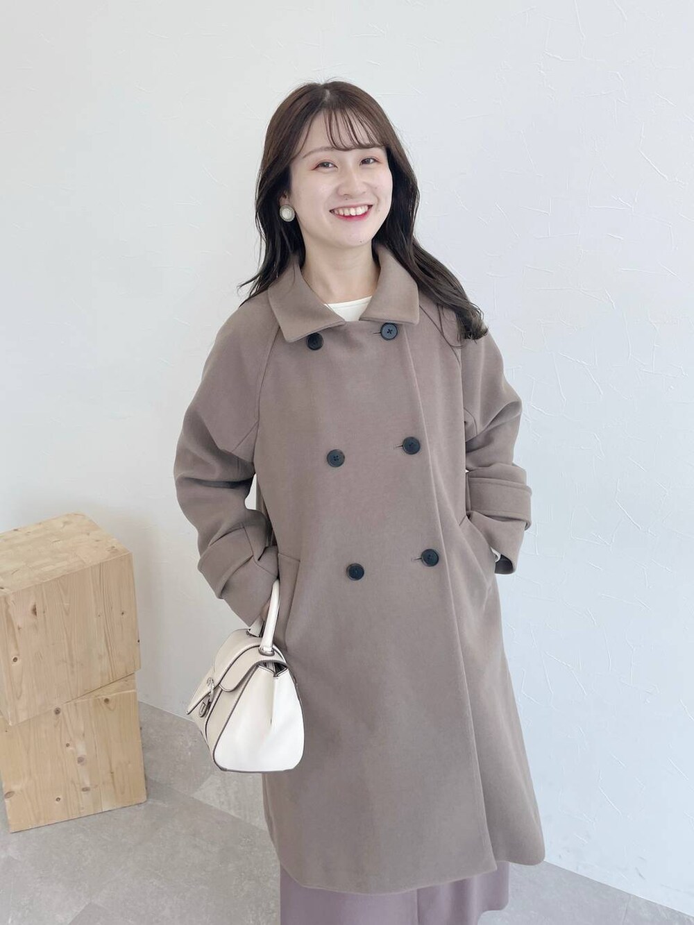 ブラウン系のチェスターコート、ホワイト系のハンドバッグ、ホワイト系のブーツを着用したレディースの夏コーディネートの4枚目の写真