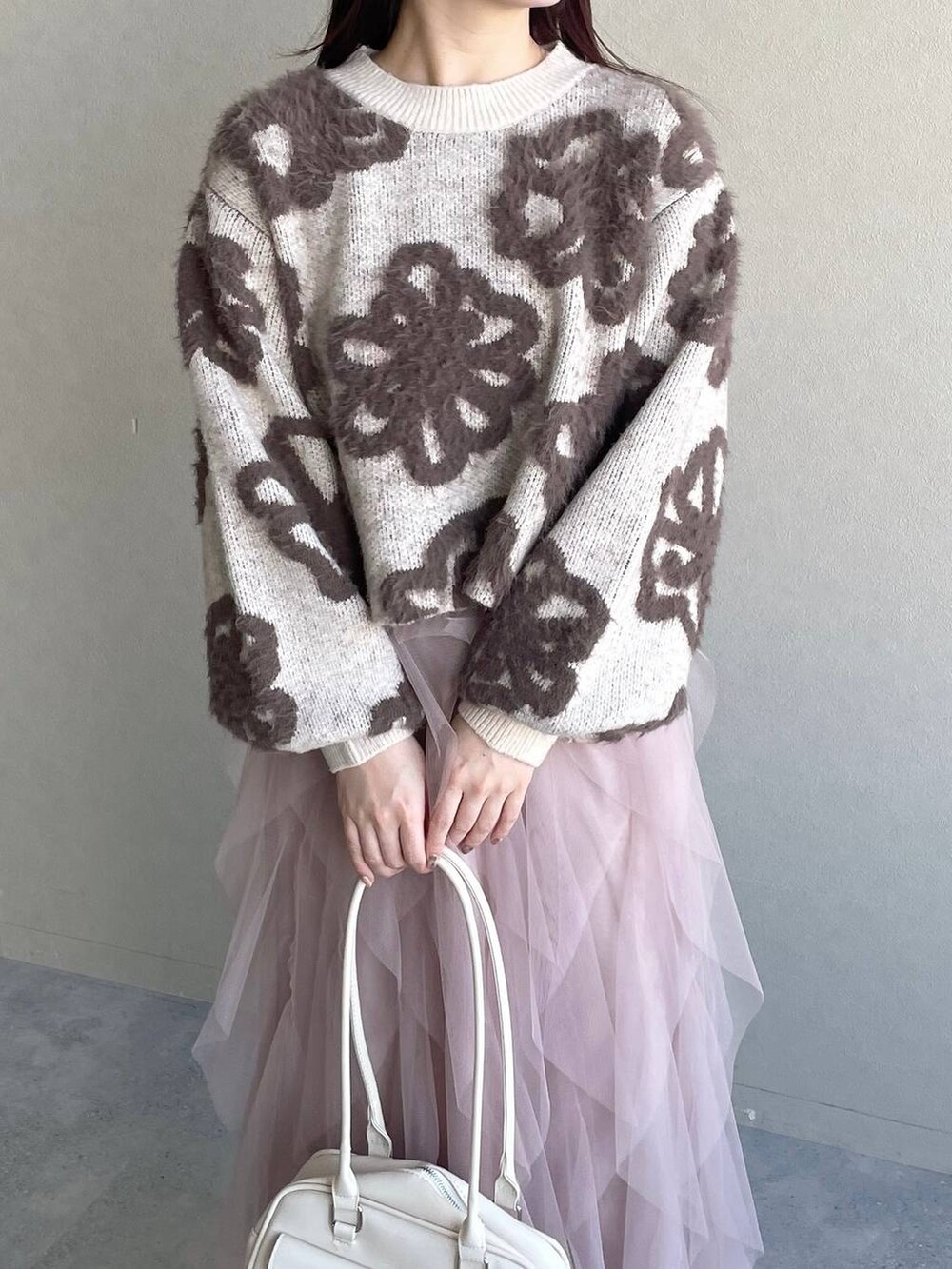 ホワイト系のニット/セーター、ホワイト系のハンドバッグ、ピンク系のスカートを着用したレディースの冬コーディネートの3枚目の写真