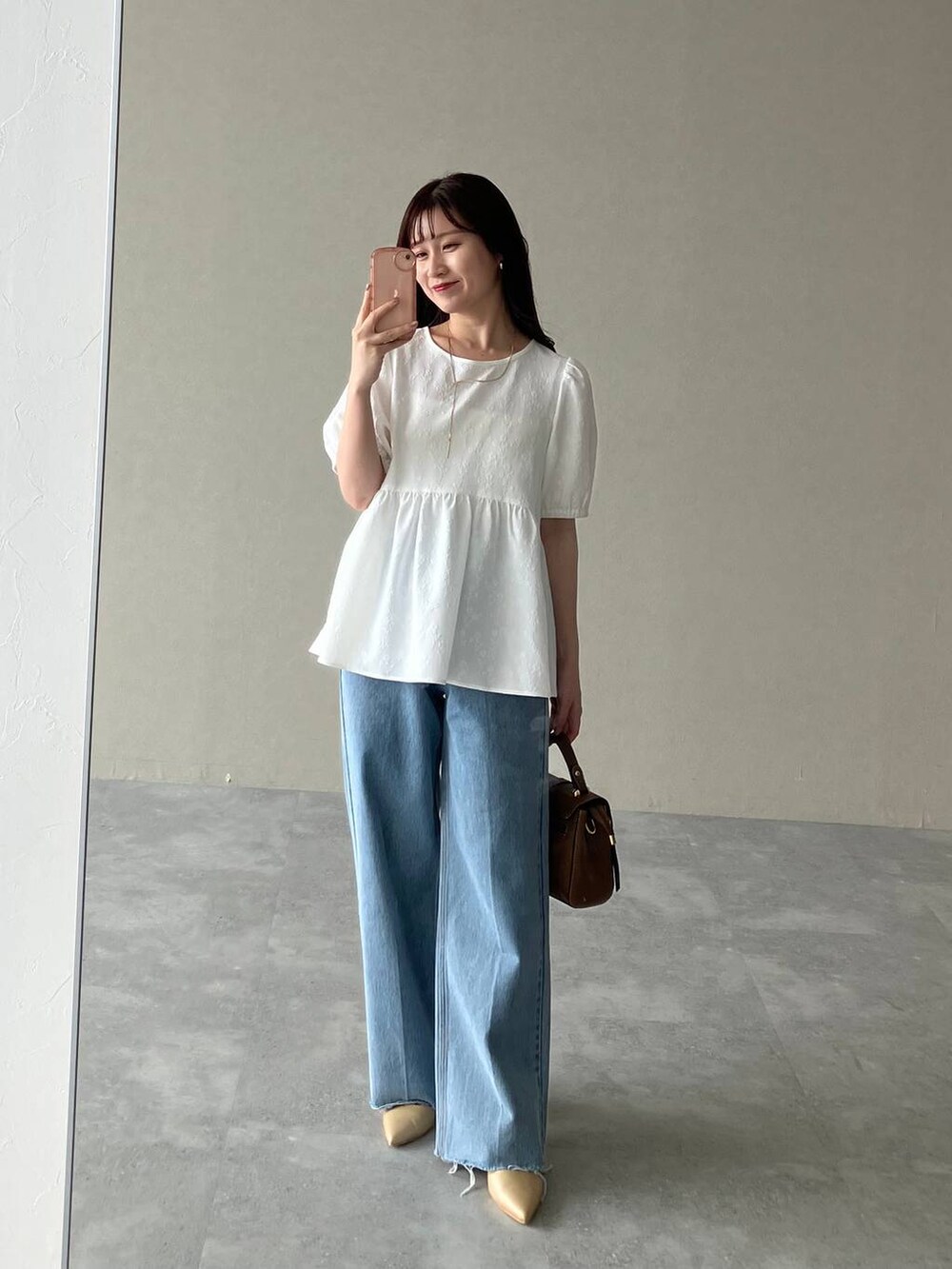 ゴールド系のパンプス、ブラウン系のショルダーバッグ、ホワイト系のシャツ/ブラウスを着用したレディースの夏コーディネートの4枚目の写真