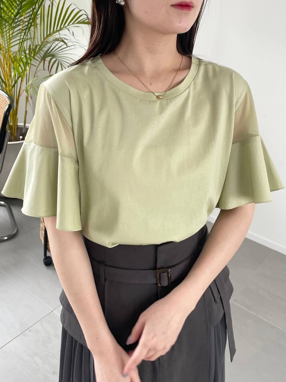 グレー系のスカート、グリーン系のTシャツ/カットソー、ブラック系のショルダーバッグを着用したレディースの春コーディネートの3枚目の写真