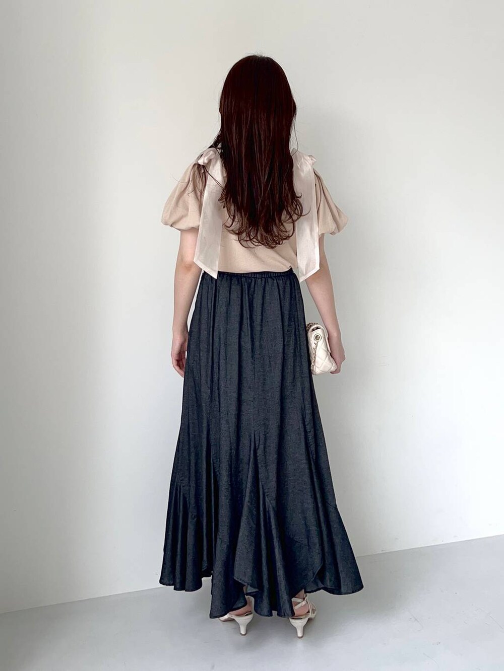 ブラック系のスカート、ホワイト系のショルダーバッグ、ホワイト系のサンダルを着用したレディースの夏コーディネートの2枚目の写真