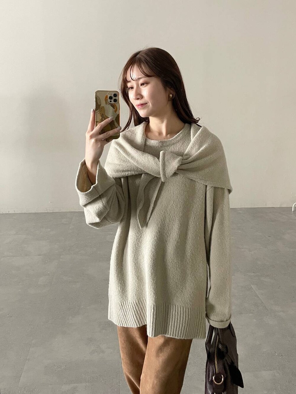 ブラウン系のボストンバッグ、ホワイト系のチェスターコート、ブラウン系のブーツを着用したレディースの秋コーディネートの4枚目の写真