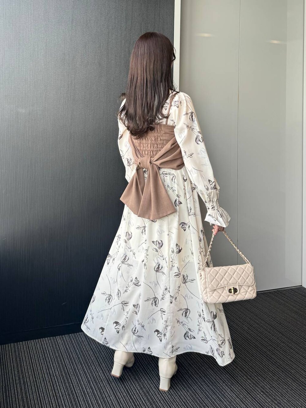 ホワイト系のショルダーバッグ、ホワイト系のワンピース、ホワイト系のブーツを着用したレディースの冬コーディネートの3枚目の写真