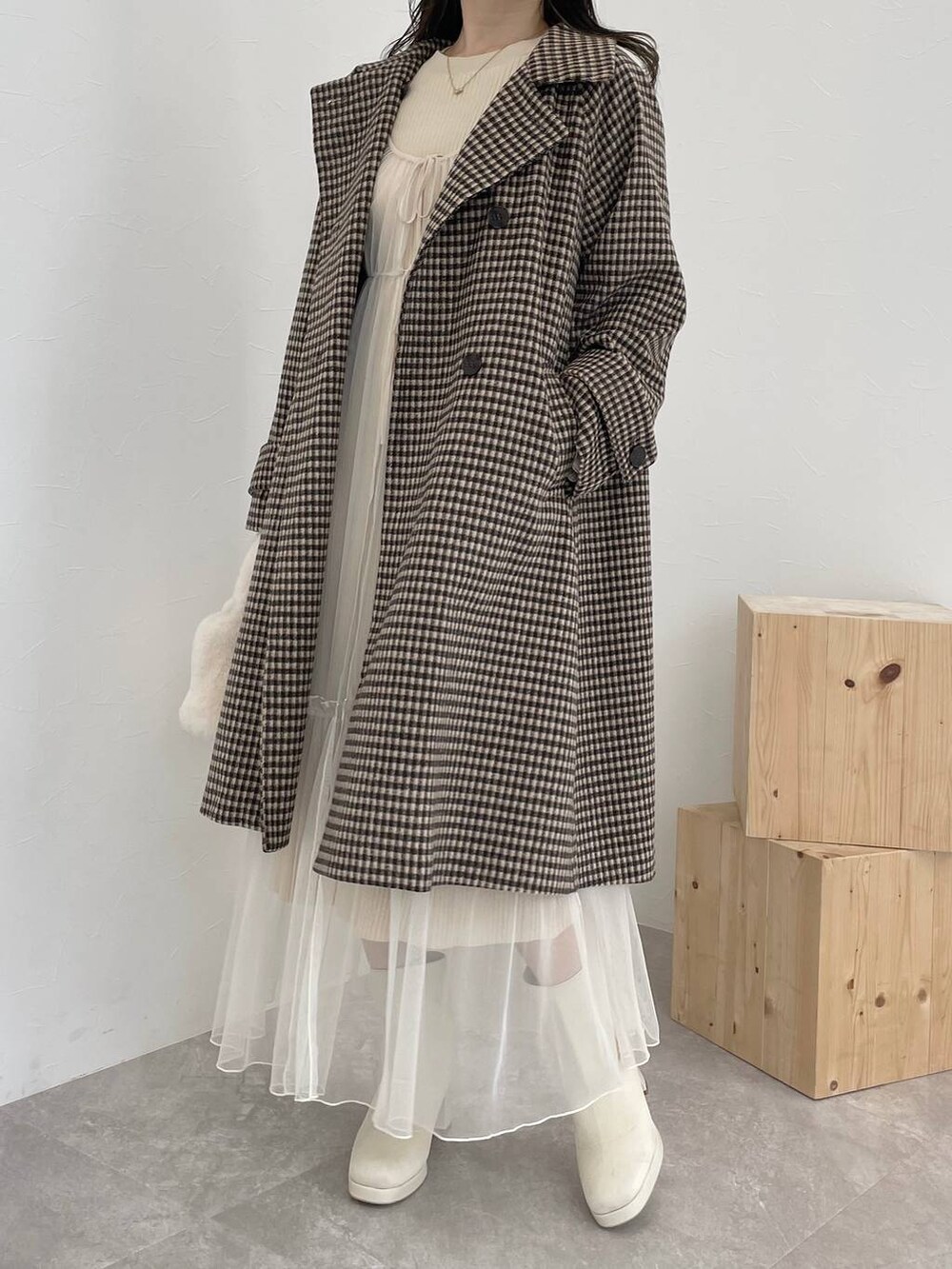 ホワイト系のブーツ、ホワイト系のハンドバッグ、ブラウン系のチェスターコートを着用したレディースの秋コーディネートの4枚目の写真