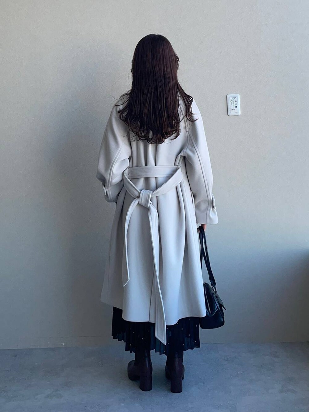 ホワイト系のチェスターコート、ブラウン系のブーツ、グレー系のニット/セーターを着用したレディースの冬コーディネートの2枚目の写真