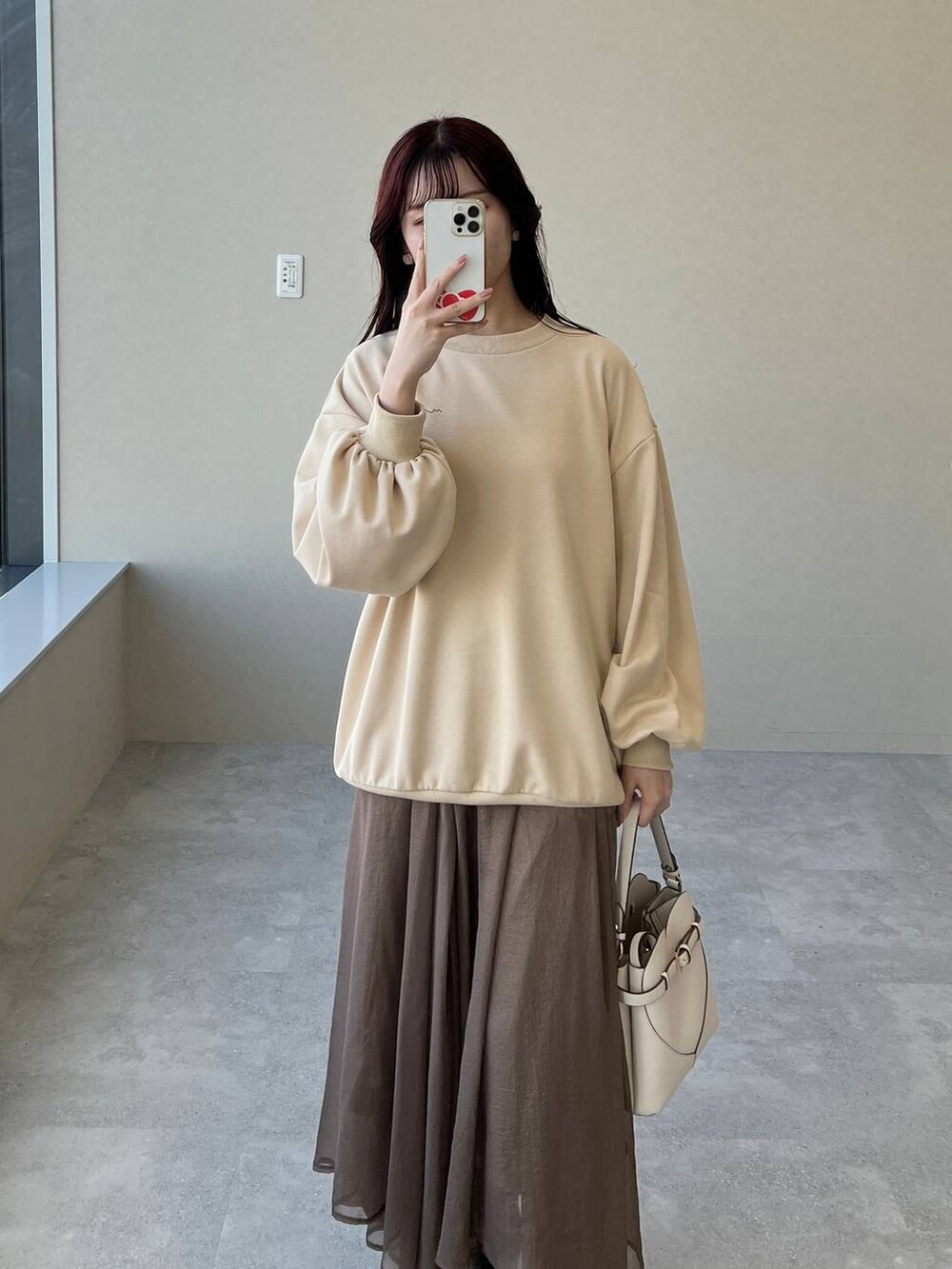 ホワイト系のショルダーバッグ、ブラウン系のブーツ、ベージュ系のスウェットを着用したレディースの冬コーディネートの3枚目の写真