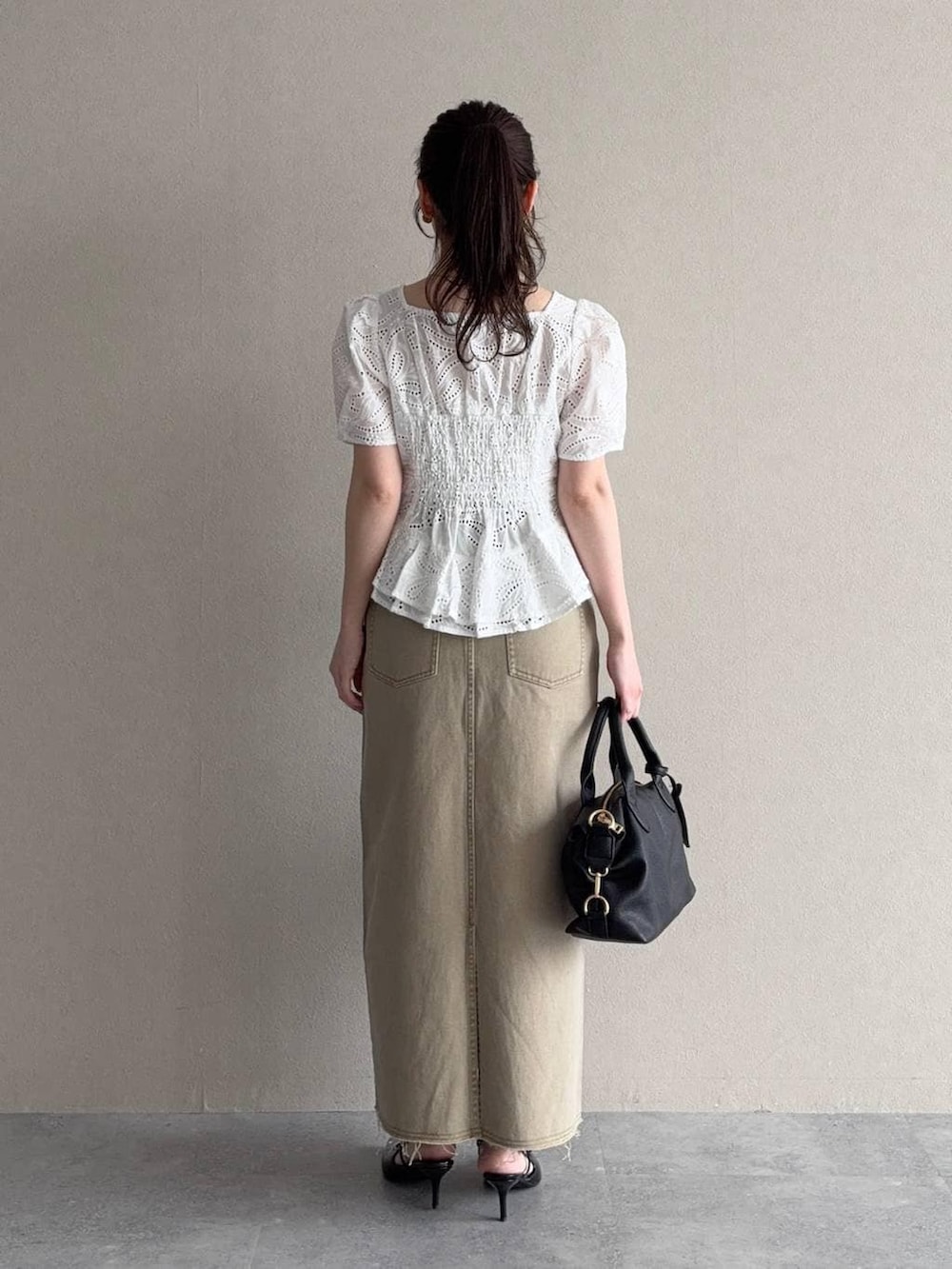 ブラック系のボストンバッグ、ブラック系のサンダル、ホワイト系のシャツ/ブラウスを着用したレディースの春コーディネートの2枚目の写真