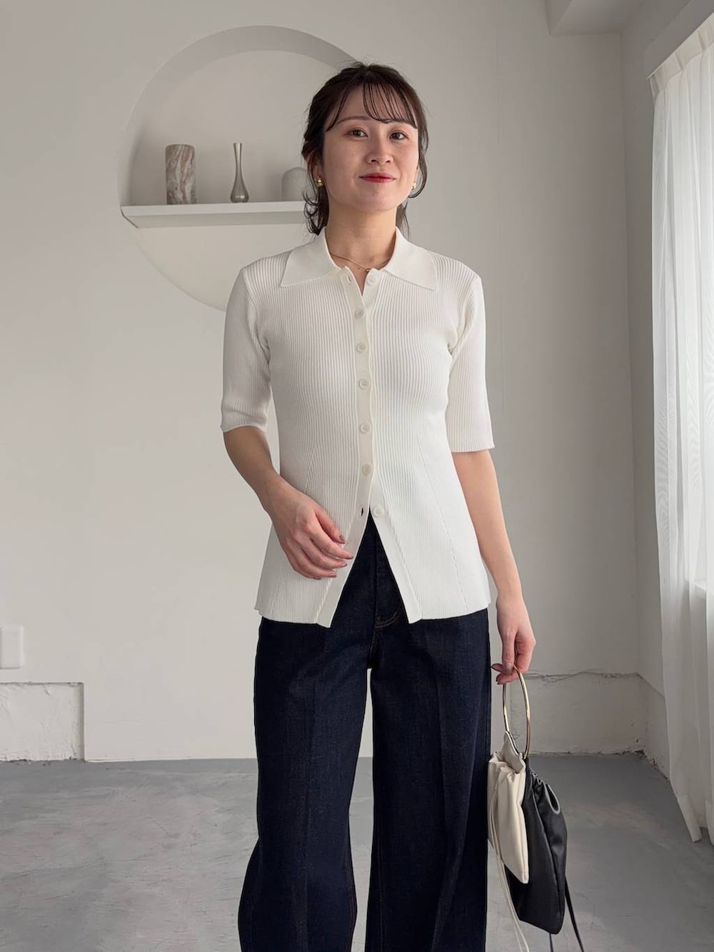 ホワイト系のサンダル、ブルー系のデニムパンツ、ブラック系のハンドバッグを着用したレディースの春コーディネートの3枚目の写真