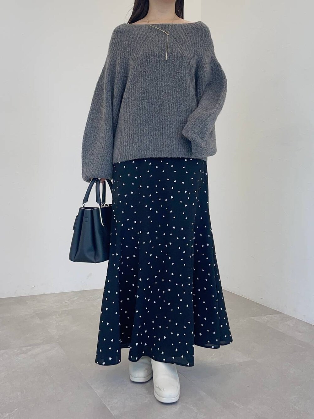 ホワイト系のブーツ、グレー系のニット/セーター、ブラック系のショルダーバッグを着用したレディースの冬コーディネートの3枚目の写真