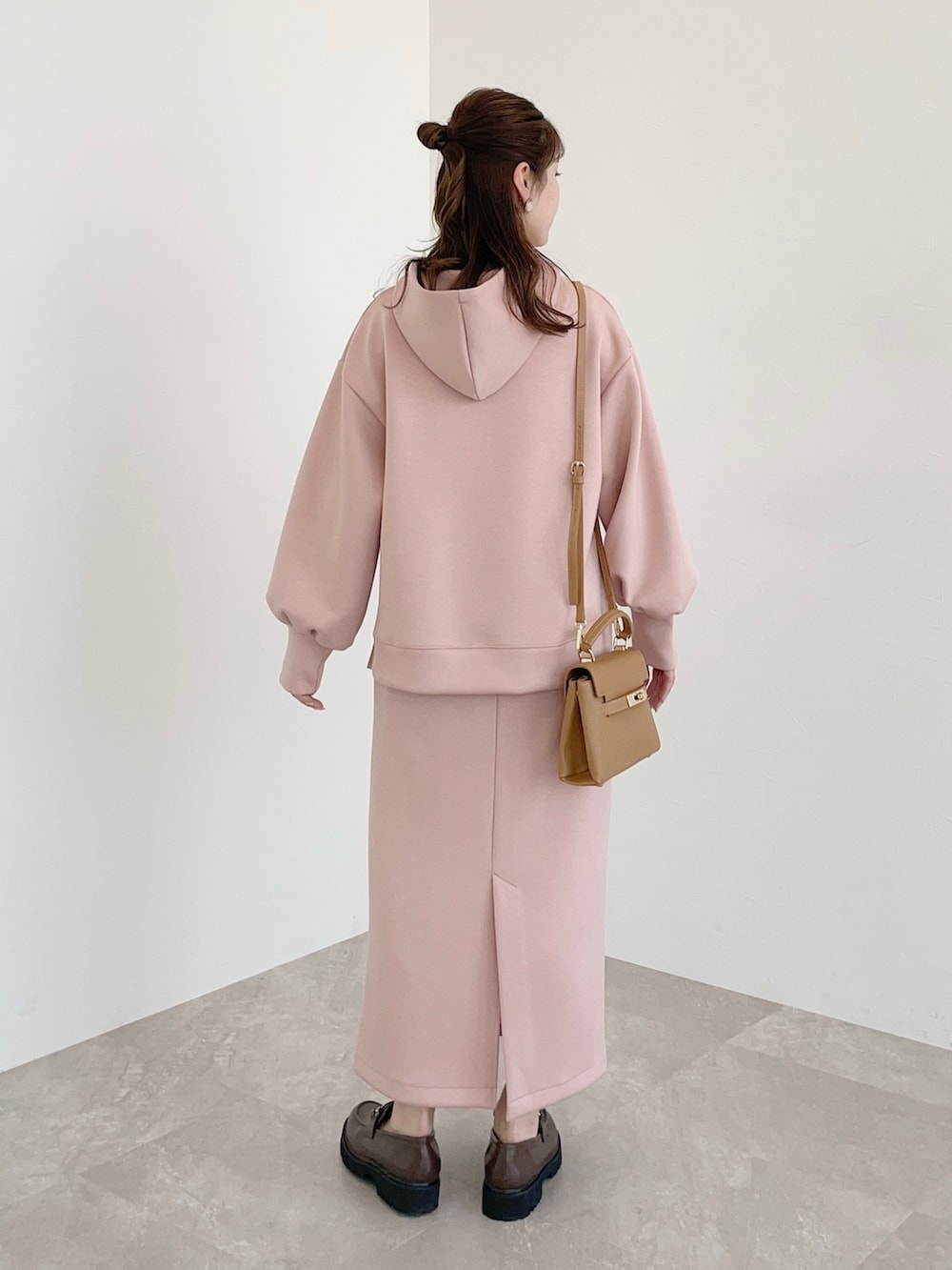 ピンク系のパーカー、ピンク系のスカート、ブラウン系のショルダーバッグを着用したレディースの春コーディネートの2枚目の写真