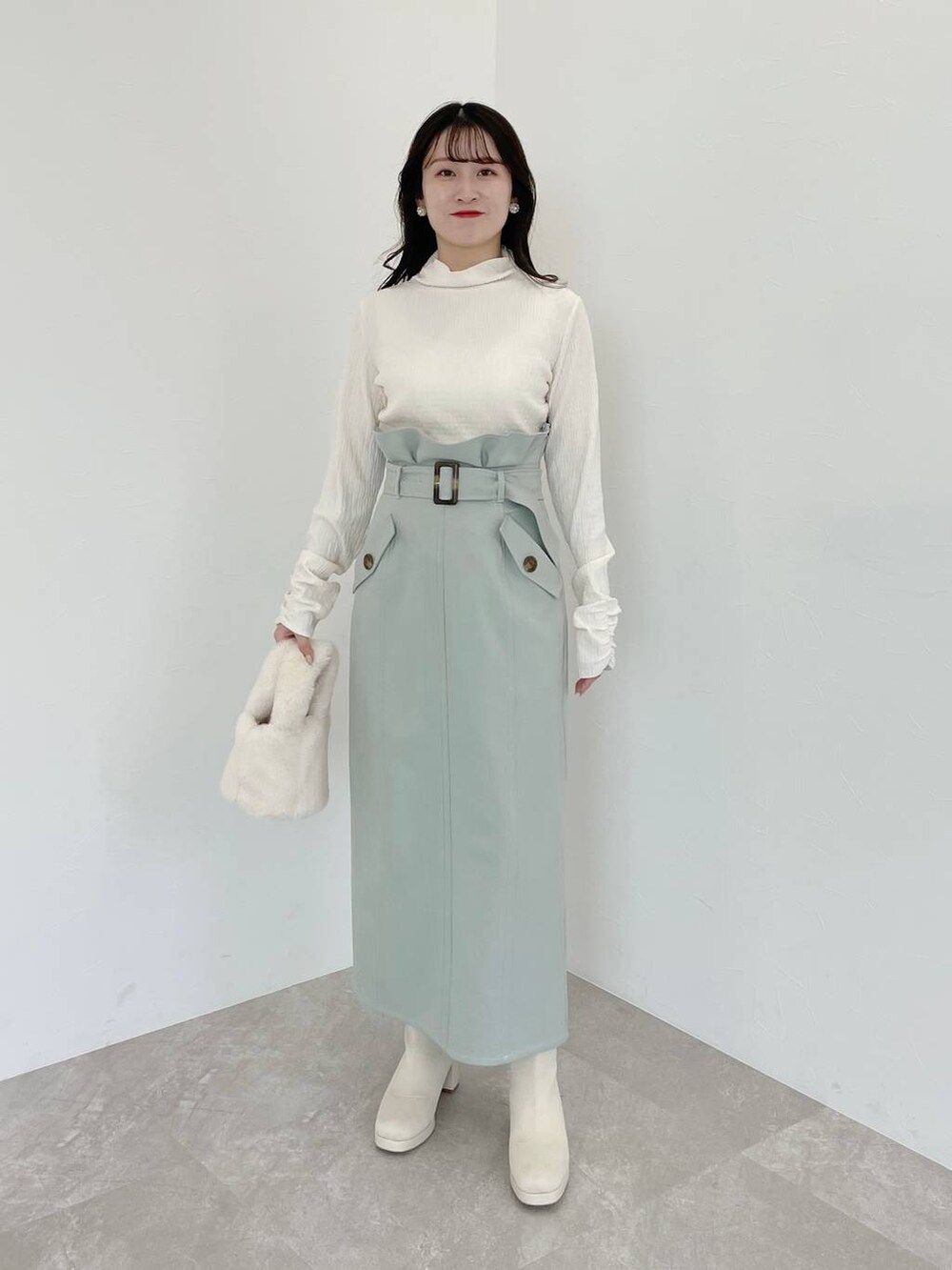 ホワイト系のブーツ、ホワイト系のハンドバッグ、グリーン系のスカートを着用したレディースの冬コーディネートの5枚目の写真