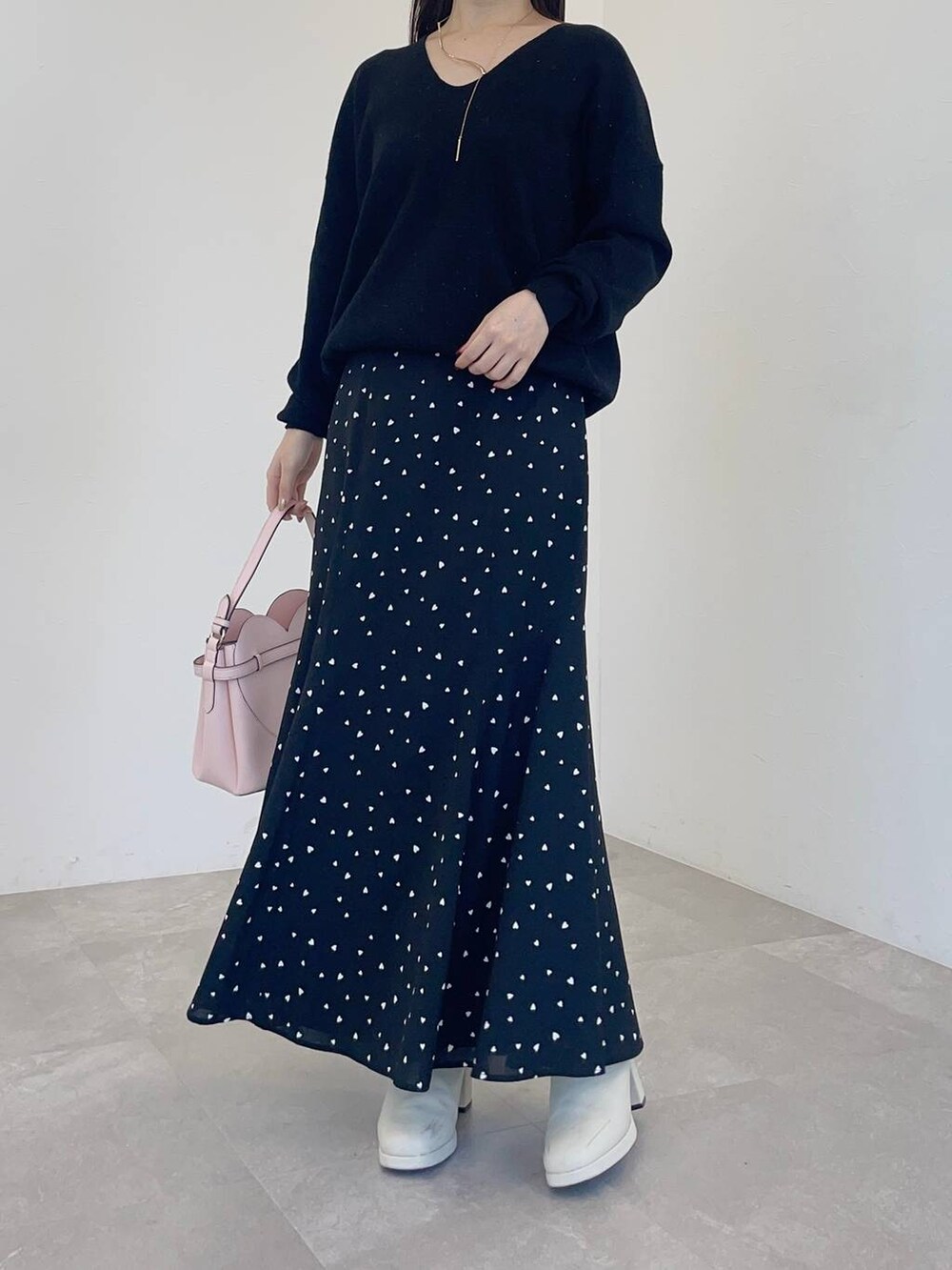 ピンク系のショルダーバッグ、ホワイト系のブーツ、ブラック系のニット/セーターを着用したレディースの冬コーディネートの4枚目の写真