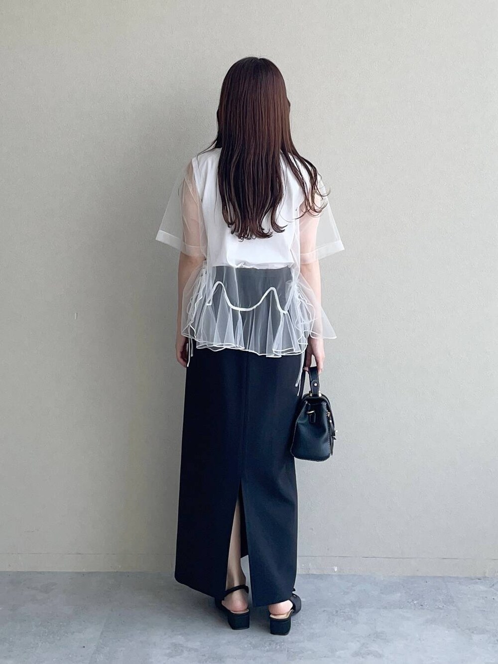 ブラック系のサンダル、ブラック系のショルダーバッグ、ホワイト系のTシャツ/カットソーを着用したレディースの秋コーディネートの2枚目の写真