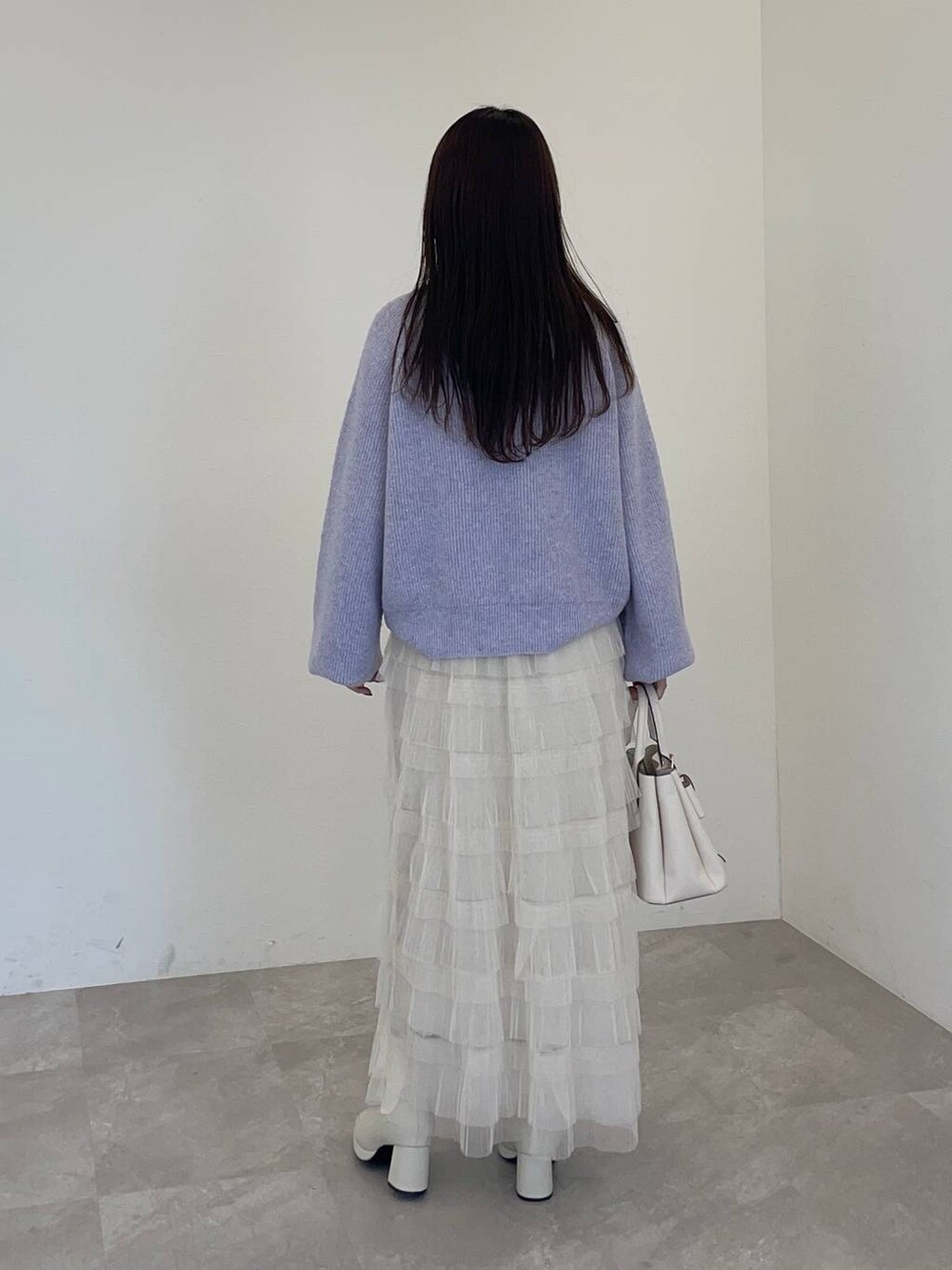 ホワイト系のブーツ、パープル系のニット/セーター、ホワイト系のスカートを着用したレディースの冬コーディネートの2枚目の写真