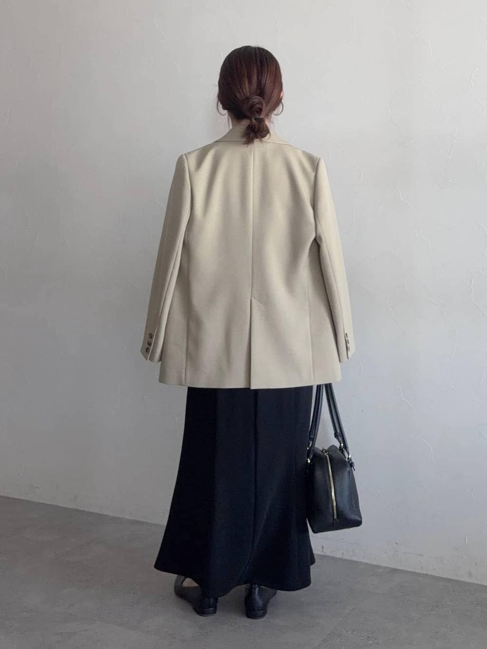 ブラック系のハンドバッグ、ベージュ系のテーラードジャケット、ブラック系のパンプスを着用したレディースの冬コーディネートの2枚目の写真