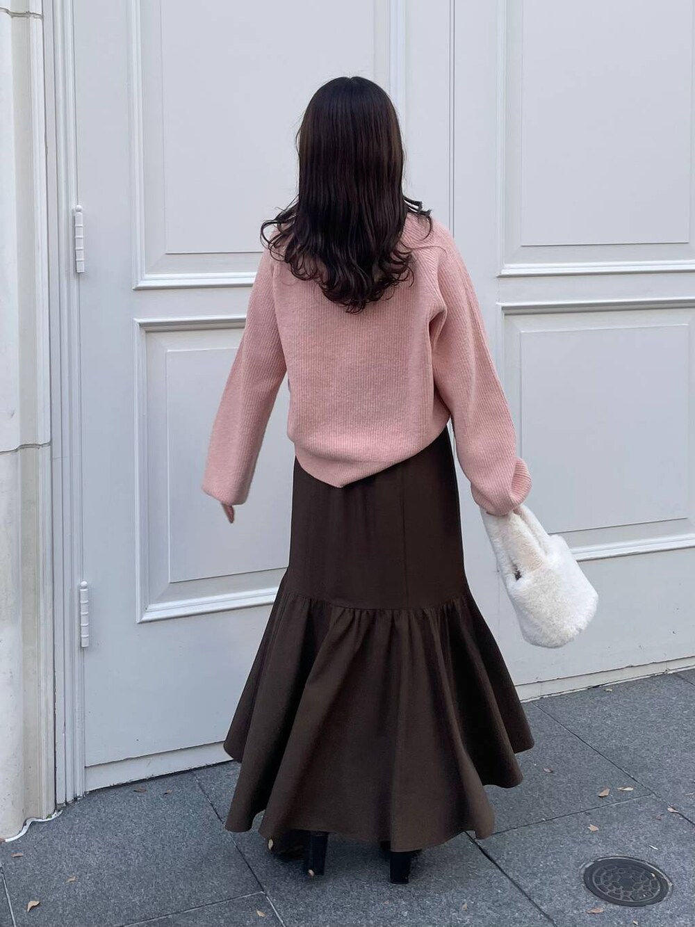 ピンク系のニット/セーター、ホワイト系のハンドバッグ、ブラウン系のスカートを着用したレディースの冬コーディネートの2枚目の写真