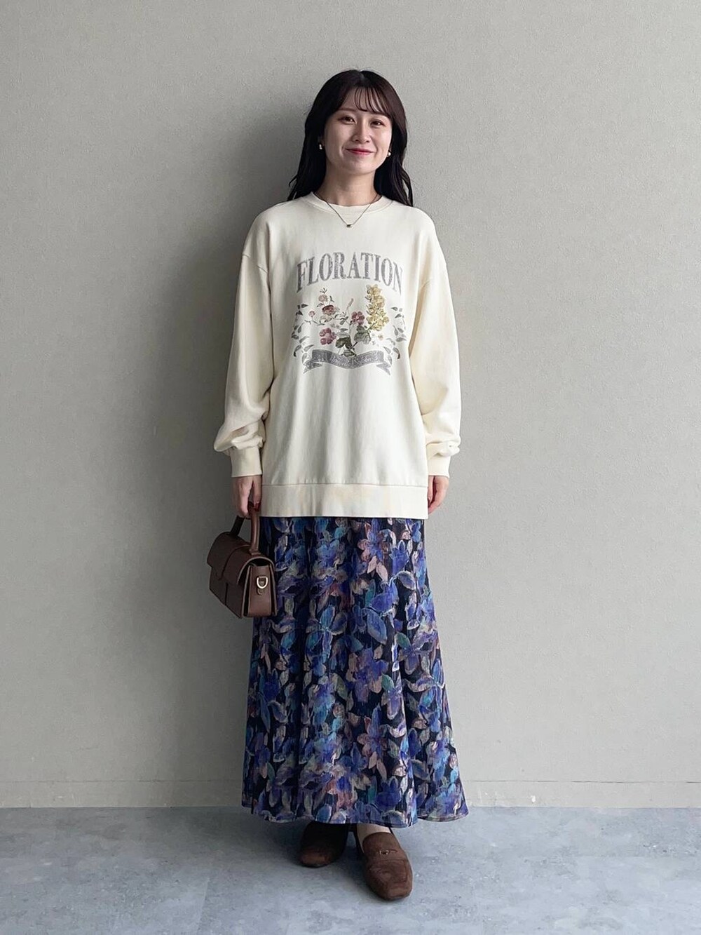 ホワイト系のスウェット、ブラック系のスカート、ブラウン系のローファーを着用したレディースの秋コーディネートの3枚目の写真