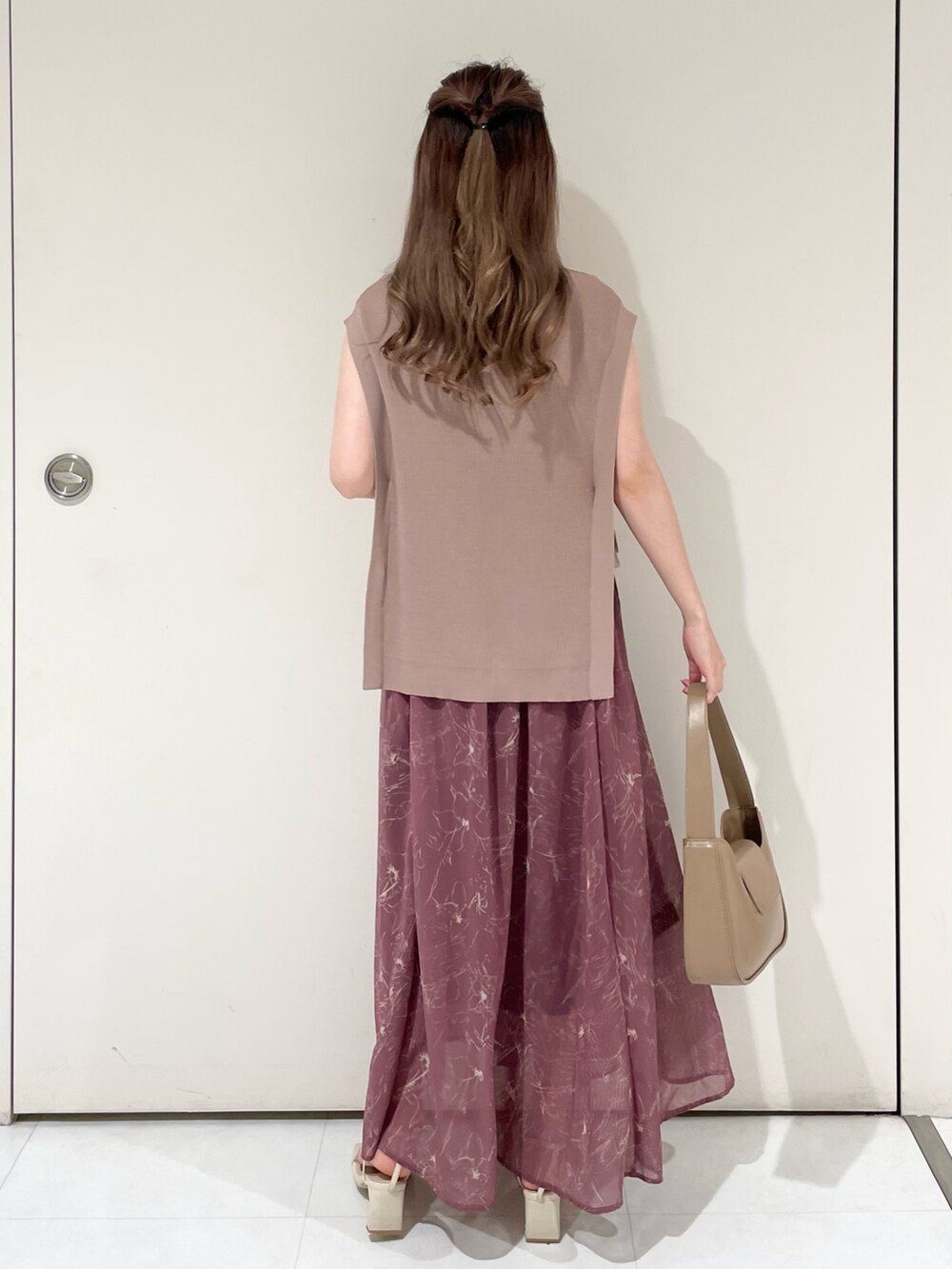 パープル系のワンピース、ブラウン系のハンドバッグ、ホワイト系のサンダルを着用したレディースの夏コーディネートの2枚目の写真