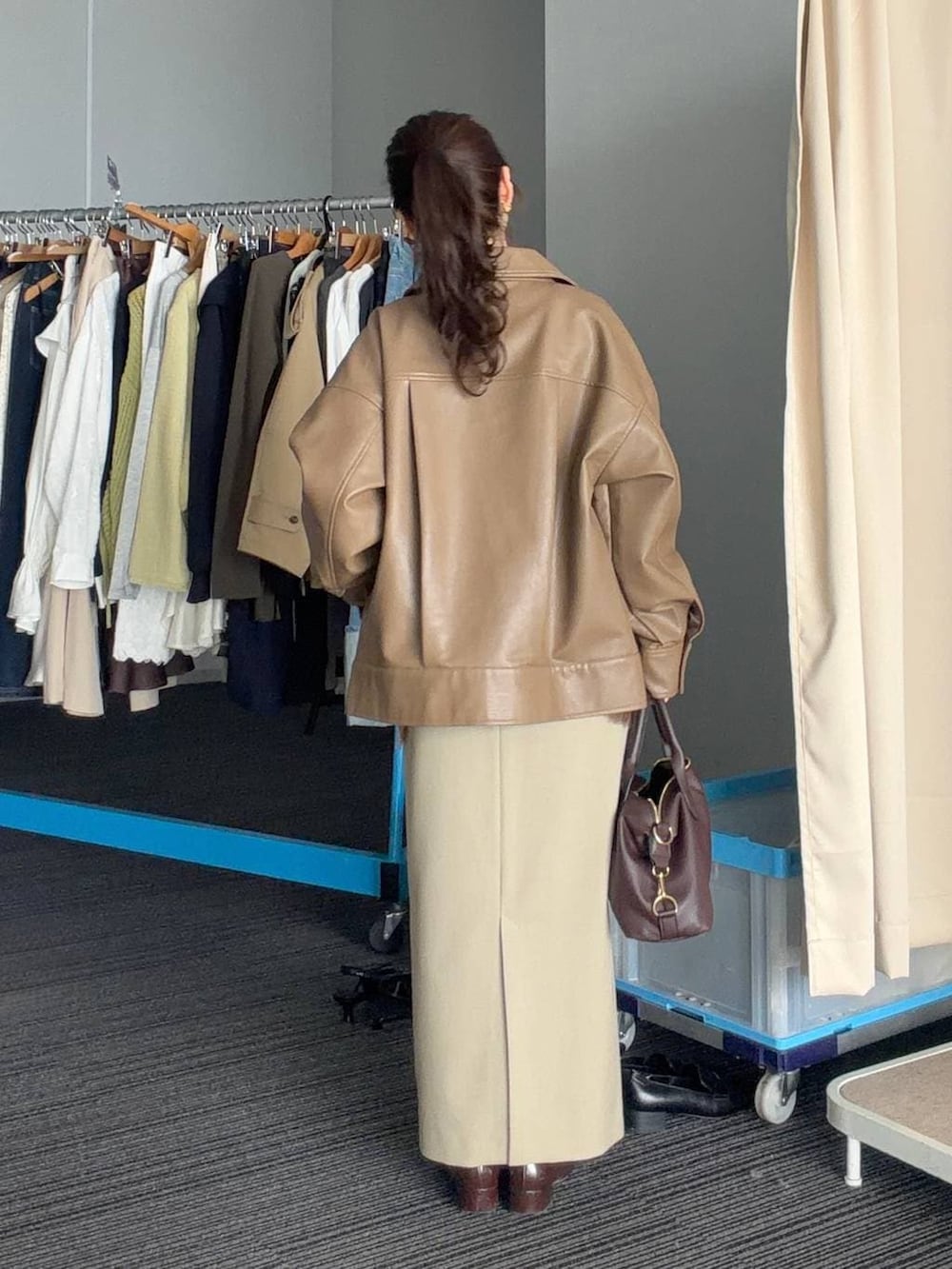 ブラウン系のボストンバッグ、ベージュ系のスカート、ブラウン系のブルゾンを着用したレディースの春コーディネートの2枚目の写真