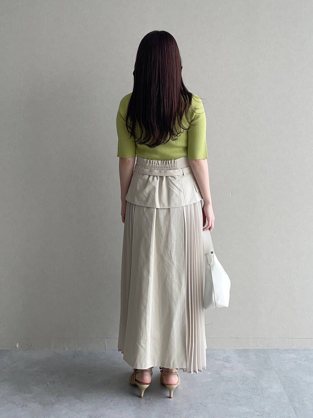 ホワイト系のスカート、グリーン系のニット/セーター、ホワイト系のショルダーバッグを着用したレディースの春コーディネートの2枚目の写真