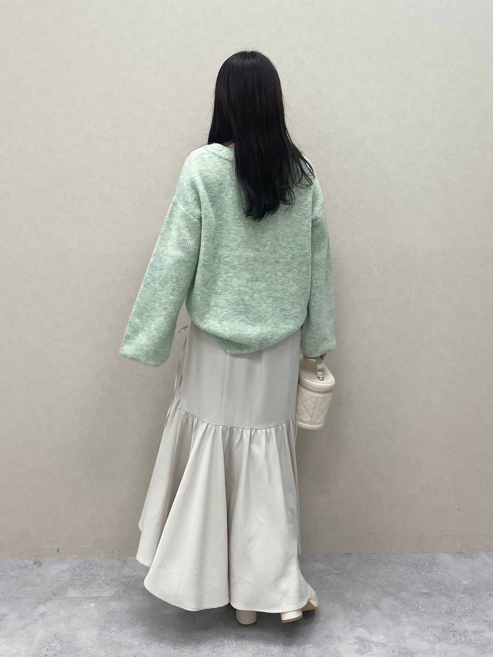 グリーン系のニット/セーター、ホワイト系のブーツ、ホワイト系のショルダーバッグを着用したレディースの冬コーディネートの3枚目の写真