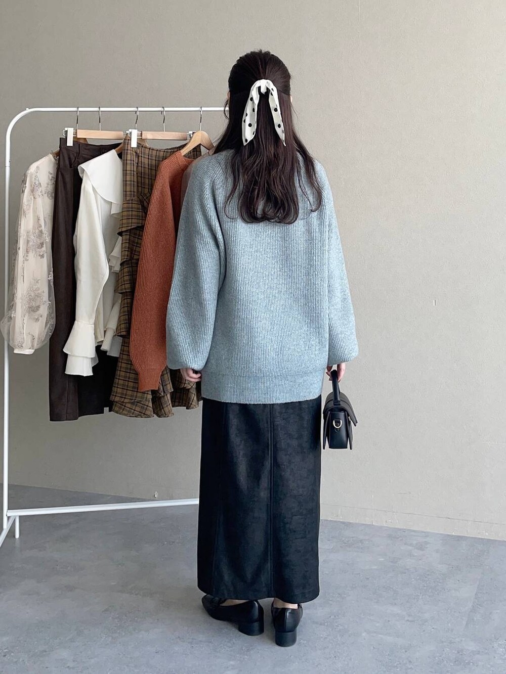 ブラック系のスカート、ブルー系のニット/セーター、ブラック系のローファーを着用したレディースの秋コーディネートの2枚目の写真