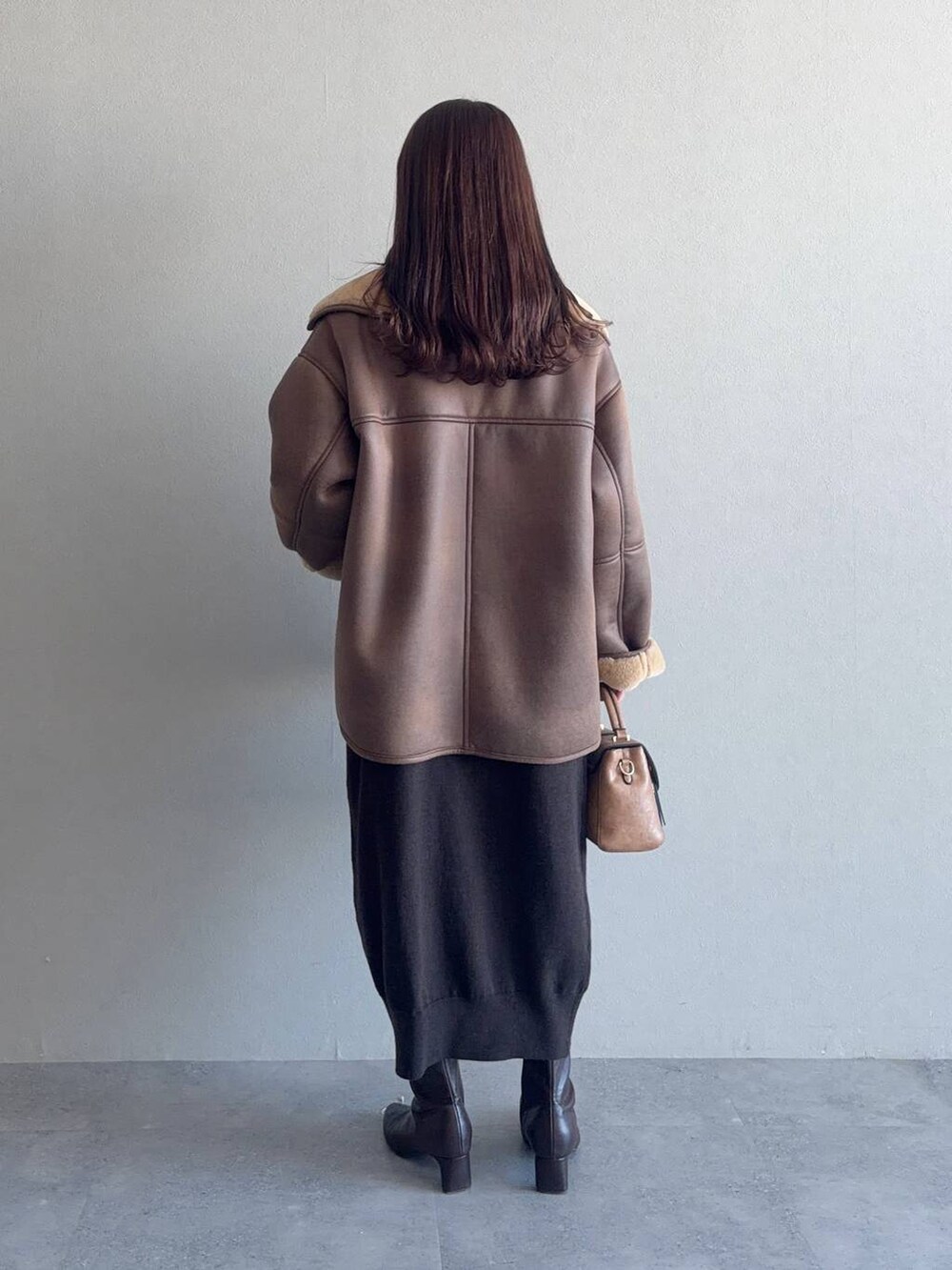 ブラウン系のブーツ、ブラウン系のブルゾン、ブラウン系のショルダーバッグを着用したレディースの冬コーディネートの2枚目の写真