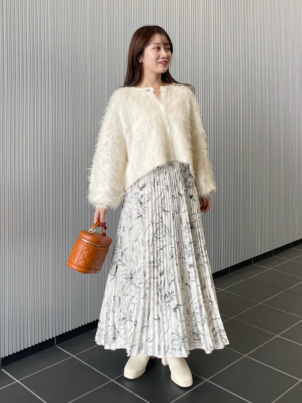 ホワイト系のカーディガン/ボレロ、ホワイト系のブーツ、オレンジ系のショルダーバッグを着用したレディースの秋コーディネートの2枚目の写真