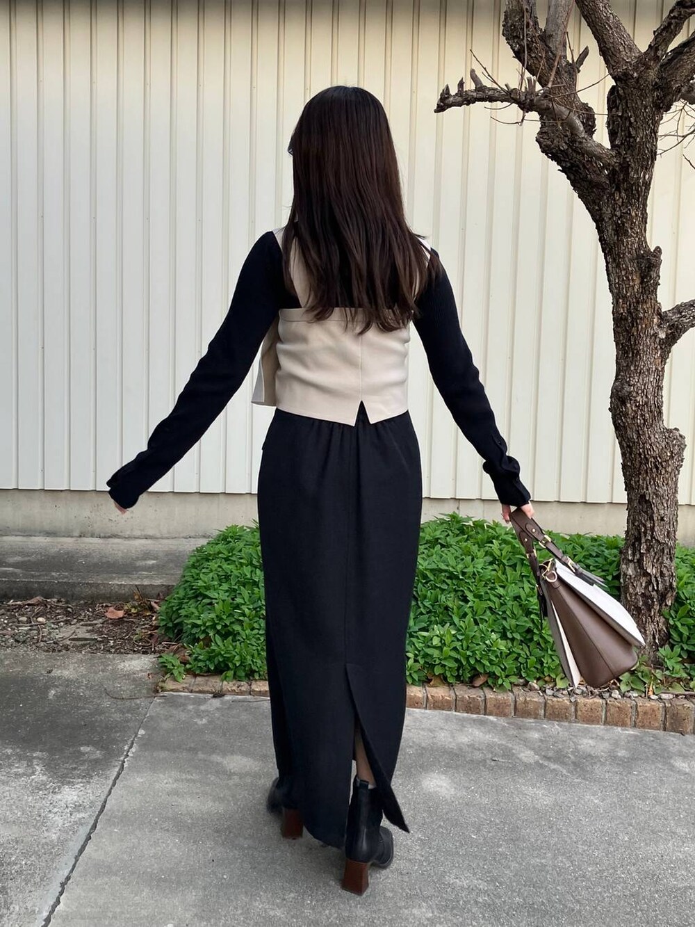 ブラック系のニット/セーター、ブラック系のスカート、ホワイト系のトートバッグを着用したレディースの冬コーディネートの2枚目の写真