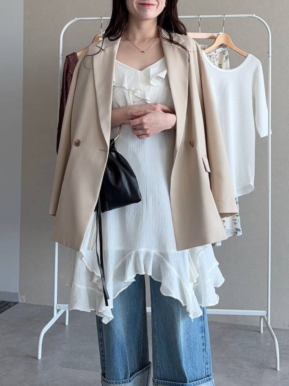 ブラック系のサンダル、ベージュ系のテーラードジャケット、ブルー系のデニムパンツを着用したレディースの春コーディネートの3枚目の写真