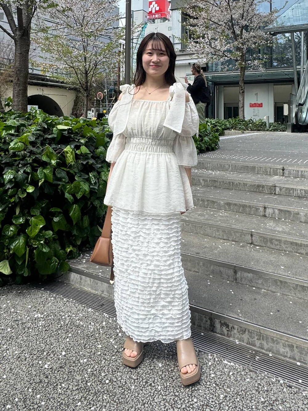 ベージュ系のサンダル、ホワイト系のスカート、ブラウン系のショルダーバッグを着用したレディースの春コーディネートの3枚目の写真