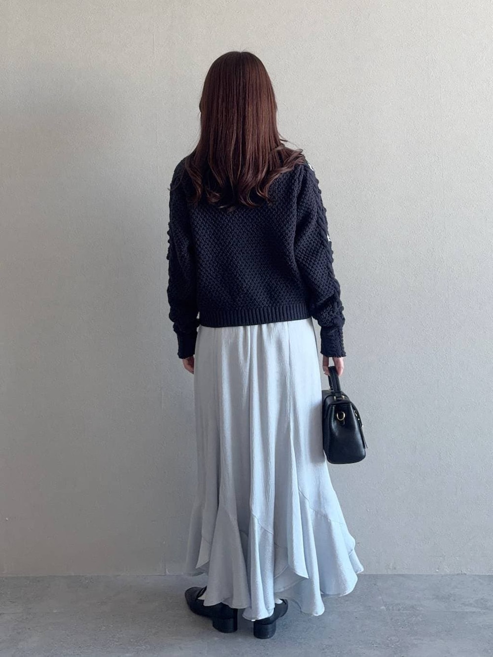 ブラック系のローファー、ブラック系のショルダーバッグ、ブルー系のスカートを着用したレディースの冬コーディネートの2枚目の写真