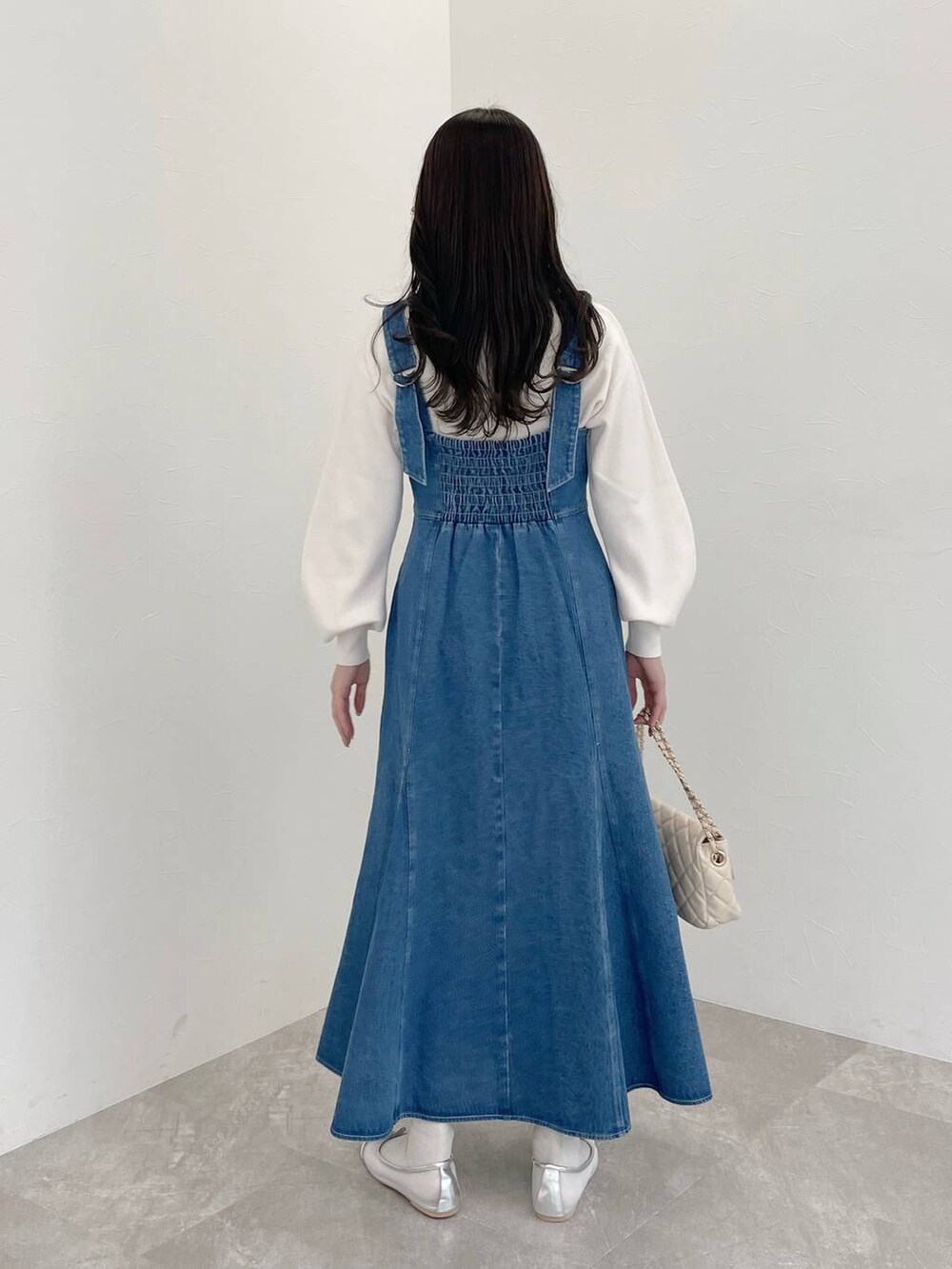 シルバー系のバレエシューズ、ホワイト系のショルダーバッグ、ブルー系のジャンパースカートを着用したレディースの春コーディネートの2枚目の写真