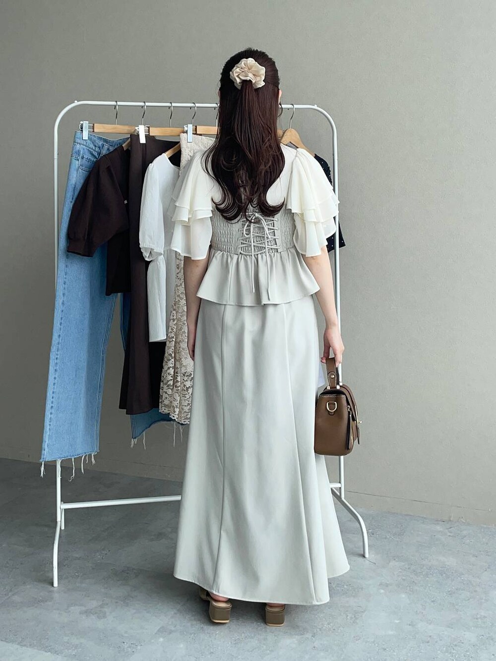 ブラウン系のサンダル、ブラウン系のショルダーバッグ、ホワイト系のTシャツ/カットソーを着用したレディースの夏コーディネートの2枚目の写真