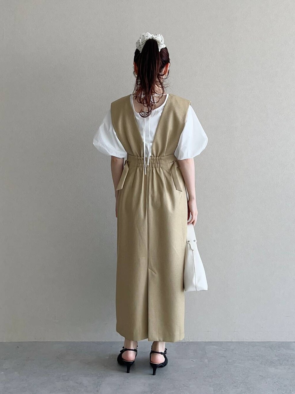 ホワイト系のショルダーバッグ、ブラック系のパンプス、ベージュ系のワンピースを着用したレディースの春コーディネートの2枚目の写真