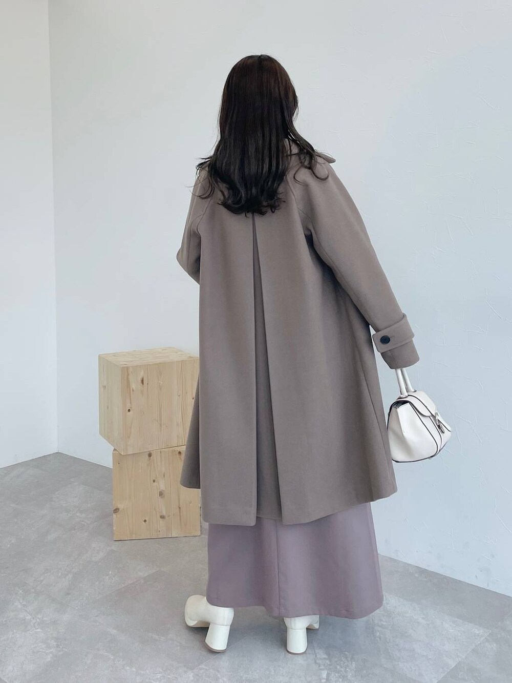 ブラウン系のチェスターコート、ホワイト系のハンドバッグ、ホワイト系のブーツを着用したレディースの夏コーディネートの3枚目の写真