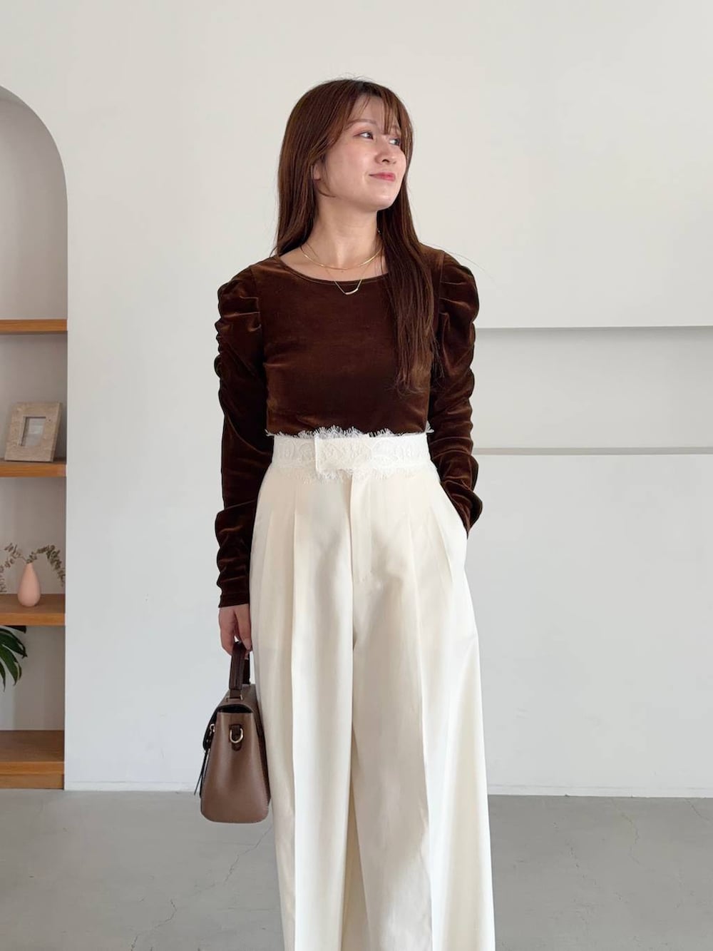 ブラウン系のTシャツ/カットソー、ベージュ系のショルダーバッグ、ブラック系のトレンチコートを着用したレディースの秋コーディネートの5枚目の写真