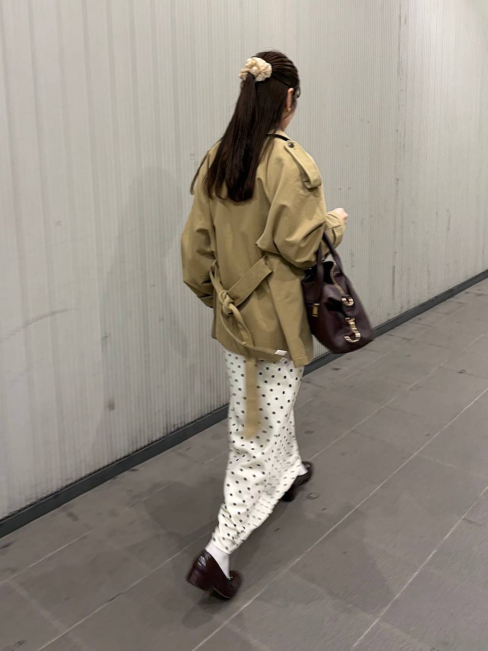 ホワイト系のスカート、ブラウン系のボストンバッグ、ベージュ系のトレンチコートを着用したレディースの冬コーディネートの3枚目の写真