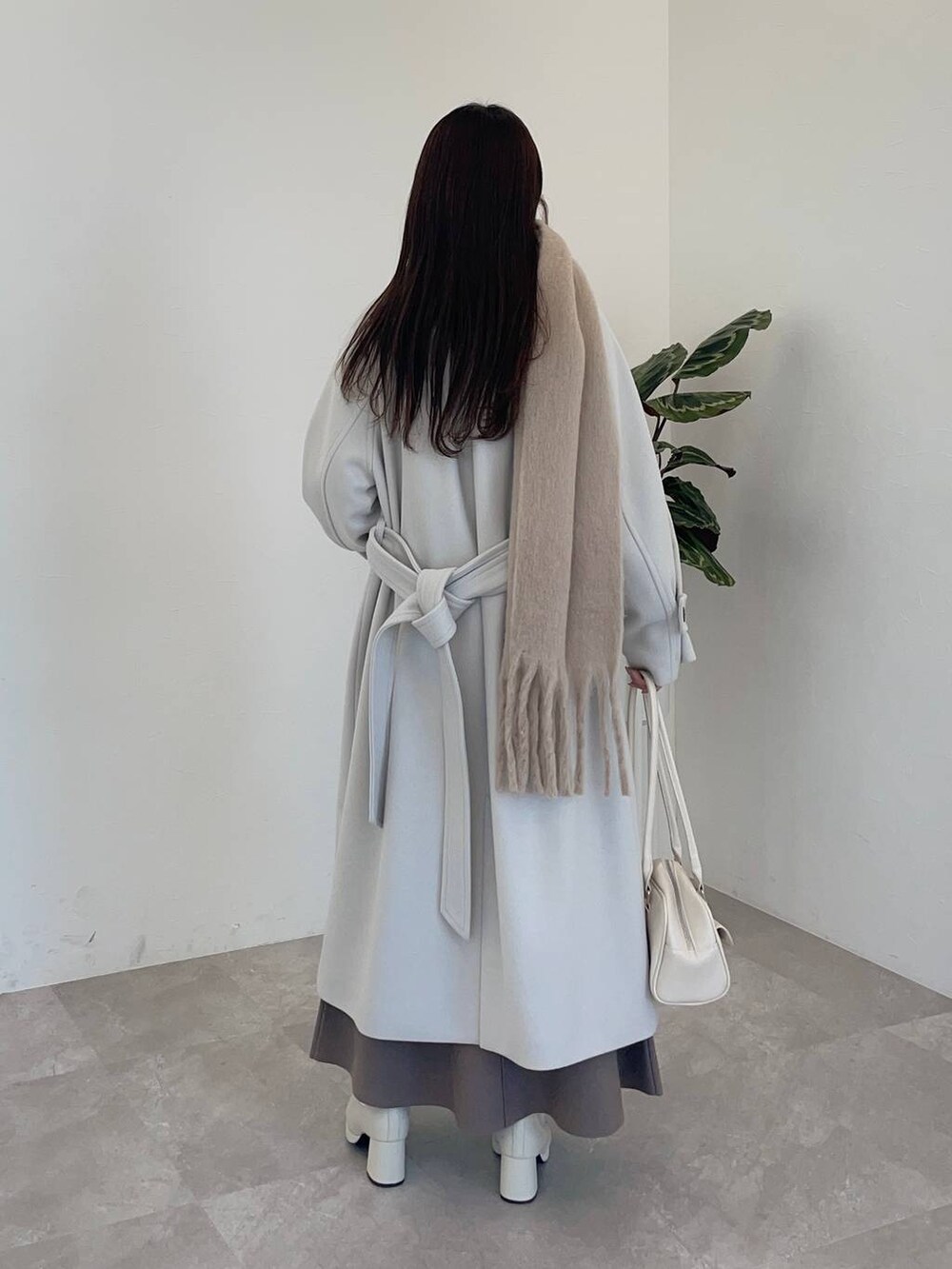 ホワイト系のチェスターコート、ホワイト系のブーツ、ホワイト系のハンドバッグを着用したレディースの冬コーディネートの2枚目の写真