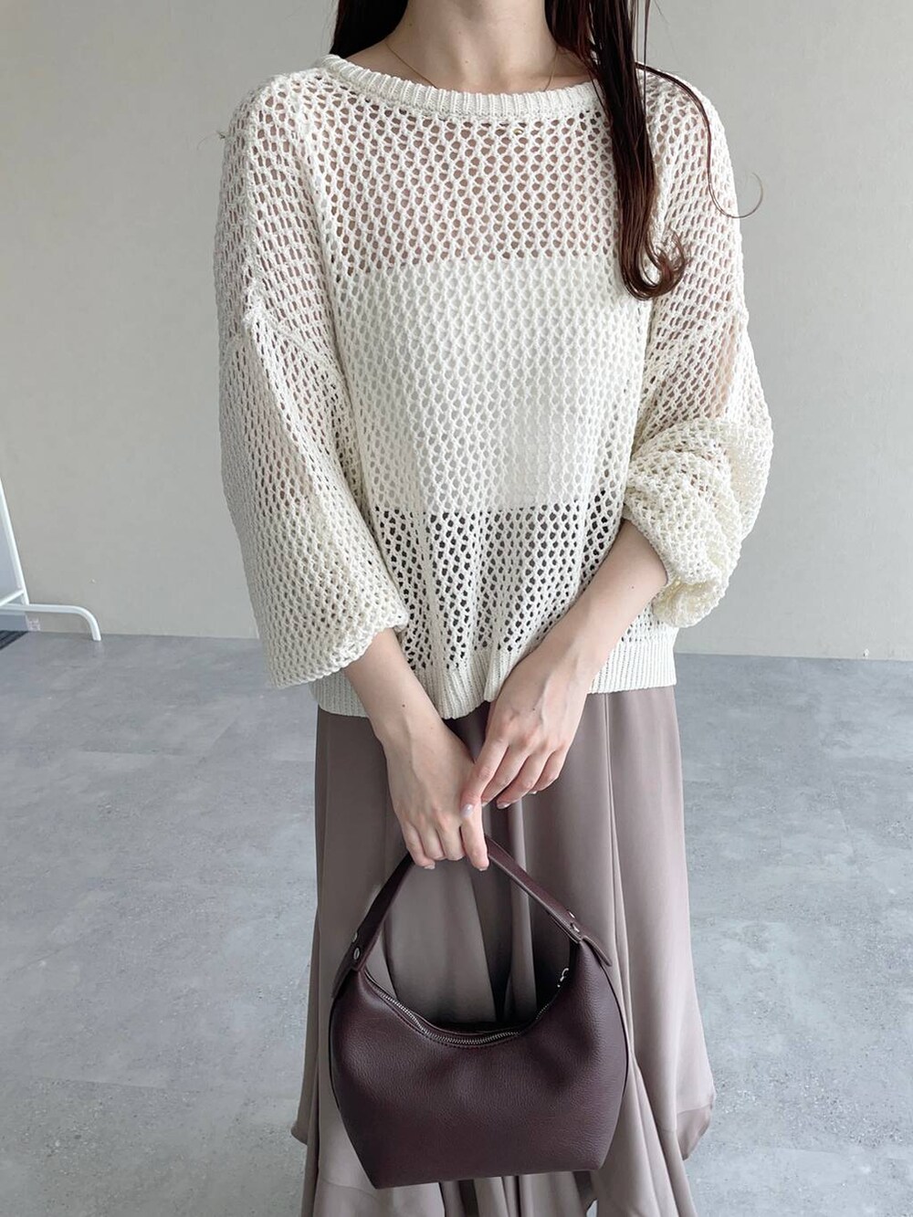 ブラウン系のショルダーバッグ、ゴールド系のパンプス、ホワイト系のニット/セーターを着用したレディースの春コーディネートの3枚目の写真