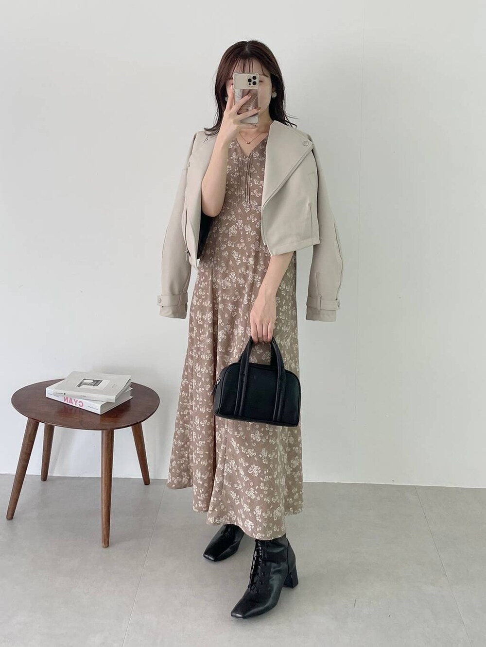 ブラック系のボストンバッグ、ブラック系のブーツ、ベージュ系のワンピースを着用したレディースの秋コーディネートの3枚目の写真