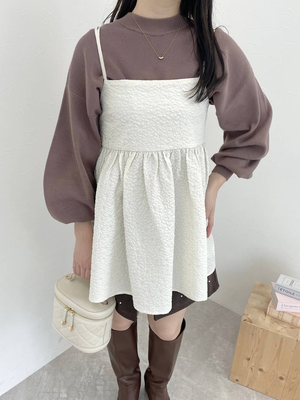 ホワイト系のキャミソール、ブラウン系のブーツ、ホワイト系のショルダーバッグを着用したレディースの冬コーディネートの3枚目の写真