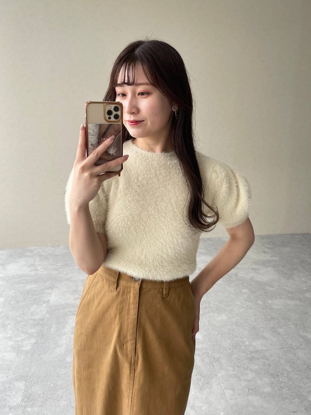 ベージュ系のニット/セーター、ホワイト系のサンダル、ブラウン系のスカートを着用したレディースの夏コーディネートの3枚目の写真