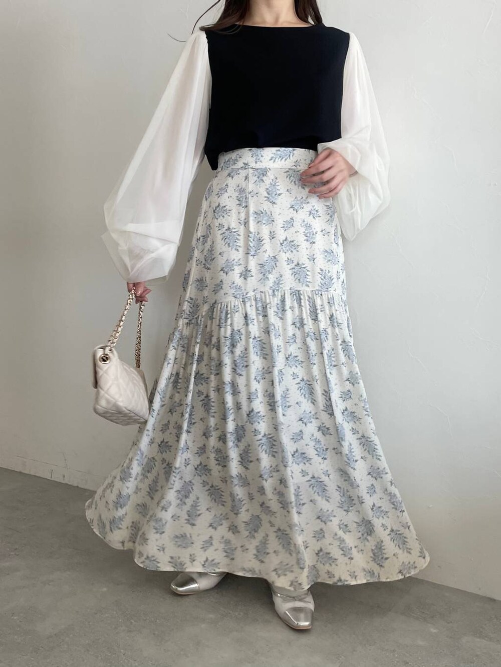 シルバー系のバレエシューズ、ブルー系のスカート、ホワイト系のショルダーバッグを着用したレディースの冬コーディネートの5枚目の写真