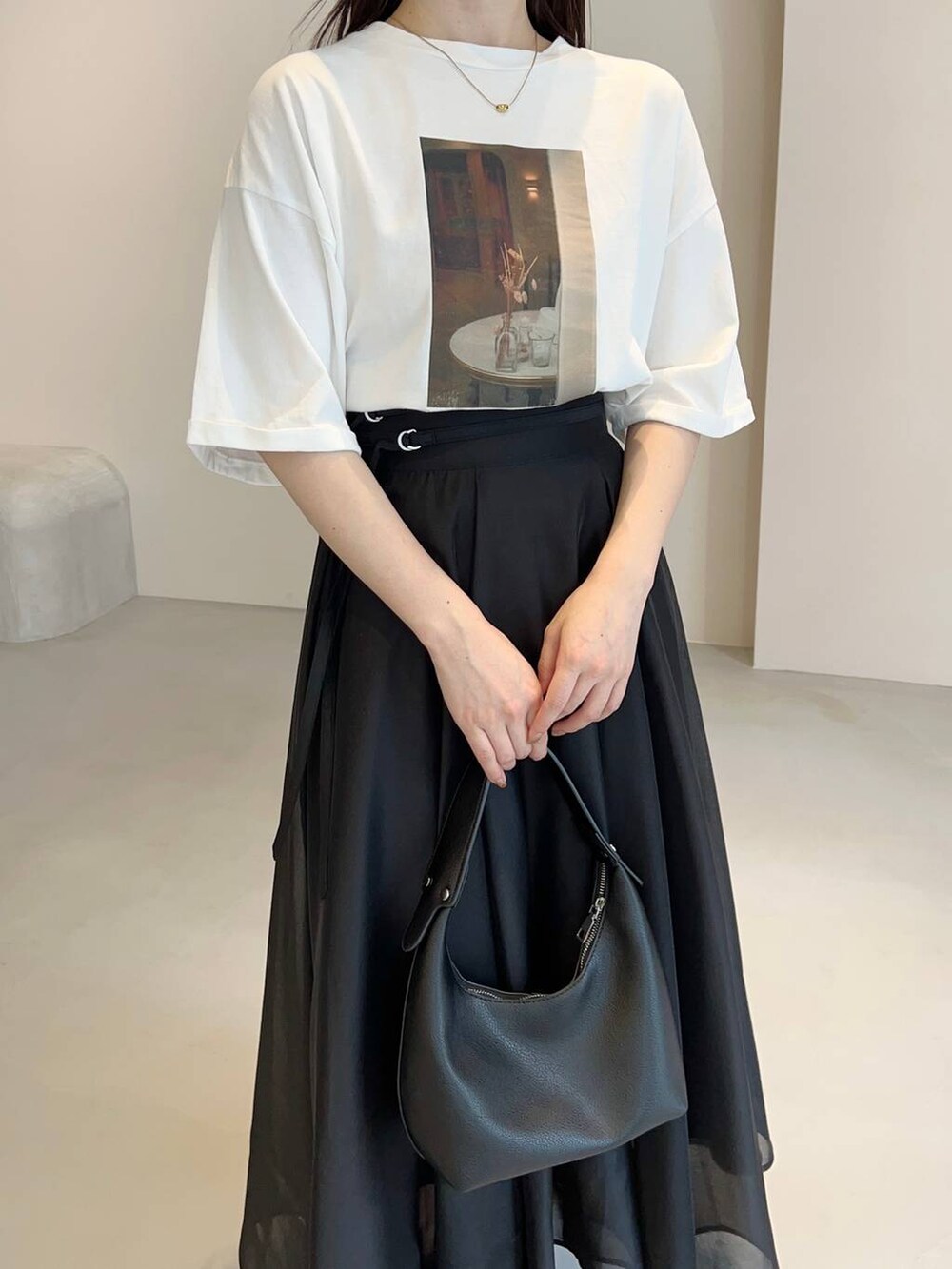 ブラック系のショルダーバッグ、ブラック系のパンプス、ホワイト系のTシャツ/カットソーを着用したレディースの夏コーディネートの3枚目の写真